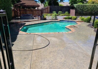 Stamped concrete around pool in backyard of house
